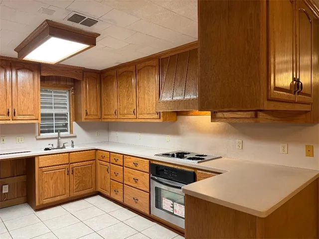 a kitchen with a sink a stove cabinets and a window