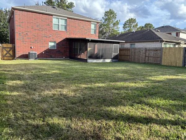 a view of a brick house with a small yard and large tree