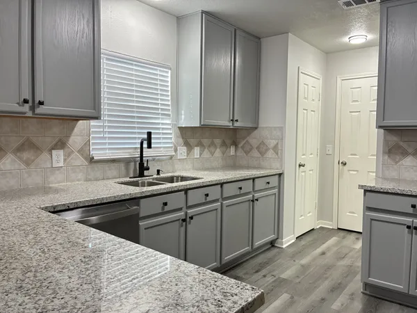 a kitchen with white cabinets and a window