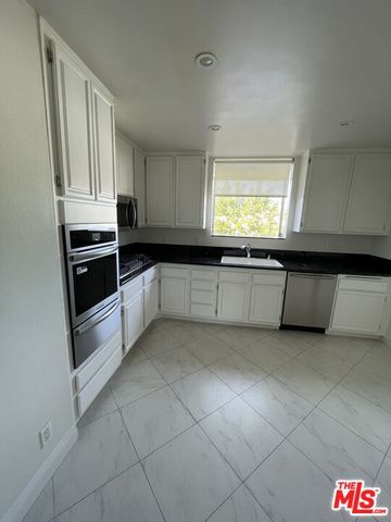a kitchen with granite countertop white cabinets and white appliances