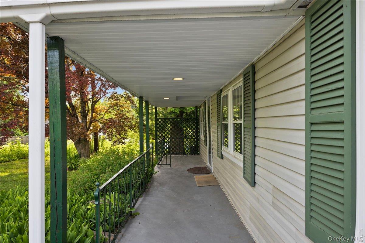 4 Brandon Road Brewster, NY 10509 - Photo 5 of 38 Covered front porch featuring a concrete surface, white vinyl siding, green louvered shutters, and recessed lighting