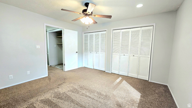8732 Fairoaks Circle Sandy, UT 84070 - Photo 13 of 18 Unfurnished bedroom with multiple closets, carpet, and a ceiling fan