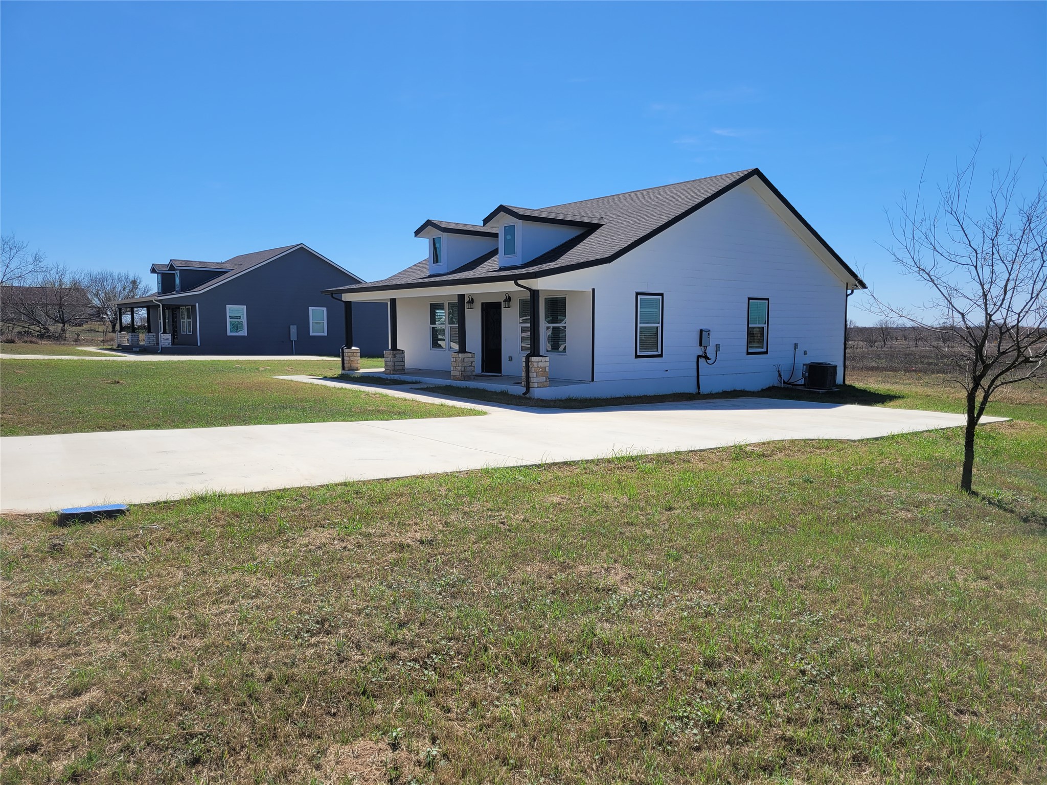 422 County Road 422 Road Stockdale, TX 78160 - Photo 4 of 37 A newly built residence with a clean, modern aesthetic, features a wide concrete driveway and inviting covered porch.