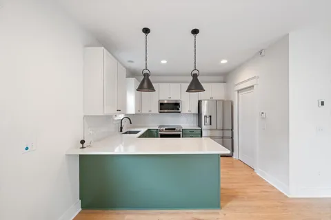 a kitchen with kitchen island a stove a sink a refrigerator and chairs