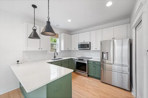 a kitchen with stainless steel appliances granite countertop a sink a stove a refrigerator and island with wooden floor