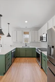 a kitchen with stainless steel appliances white cabinets and wooden floors