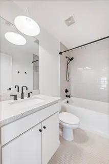 a bathroom with a granite countertop sink toilet a mirror and shower