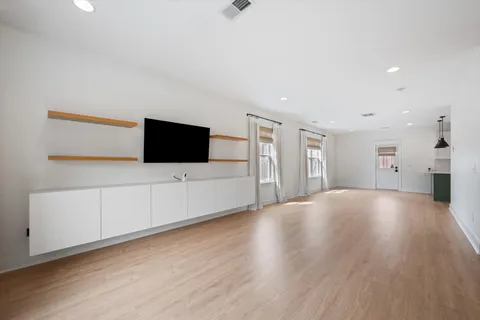 a view of an empty room with wooden floor and windows