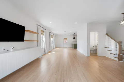 a view of an empty room with wooden floor and a flat screen tv