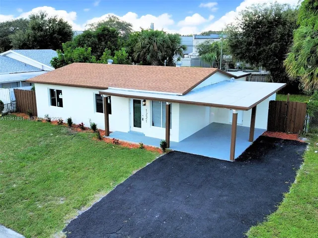 a view of a house with a yard plants and large tree
