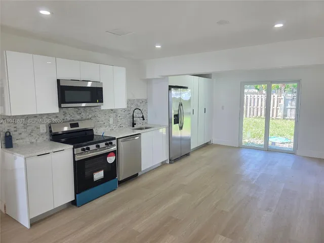 a kitchen with granite countertop a stove top oven a sink dishwasher and a refrigerator with wooden floor