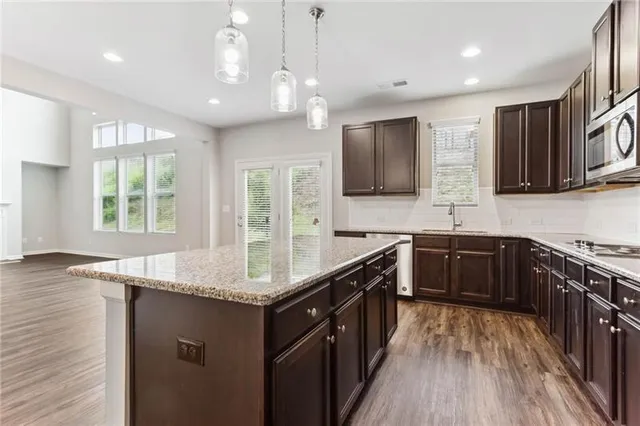 a kitchen with granite countertop a sink a counter space appliances and cabinets