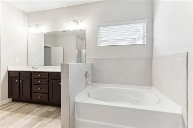 a spacious bathroom with a tub sink and mirror