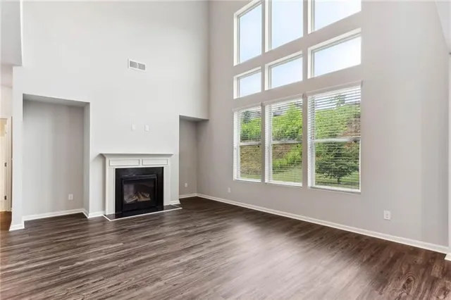 a view of an empty room with wooden floor fireplace and a window