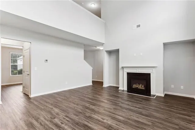 a view of an empty room with wooden floor fireplace and a window