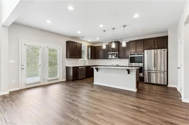 a large kitchen with stainless steel appliances kitchen island a large counter top and wooden floors