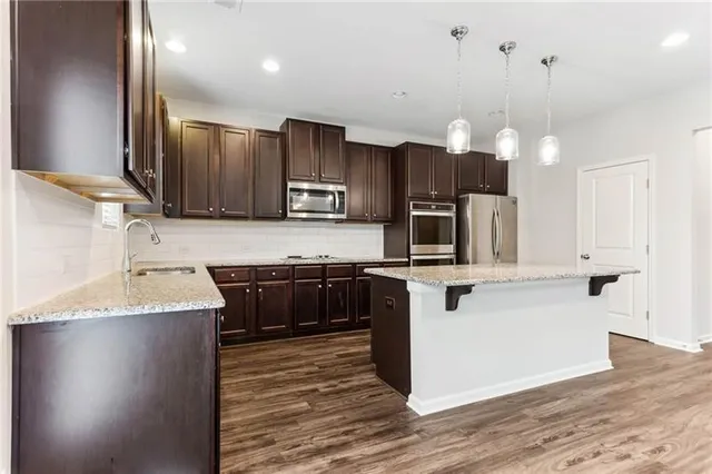 a kitchen with kitchen island granite countertop a sink a counter top space appliances and cabinets