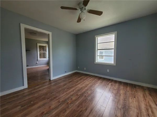 a view of an empty room with wooden floor and a window