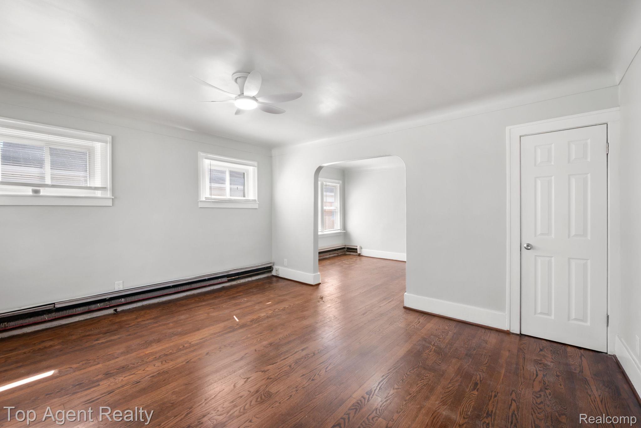 Hardwood flooring throughout, arched doorway, ceiling fan with integrated lighting, and white six-panel interior door