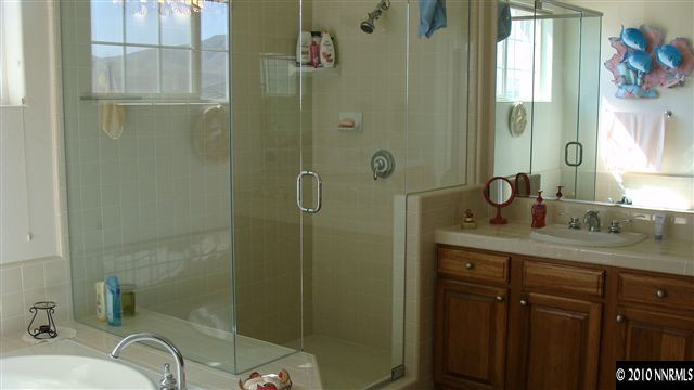 10545 Dillingham Drive Reno, NV 89521 - Photo 6 of 9 a bathroom with a granite countertop sink a mirror a shower and a bathtub