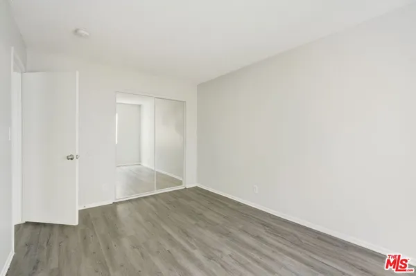 a view of an empty room with wooden floor and closet