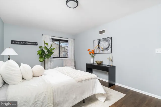a bedroom with a bed a painting on the wall and a potted plant
