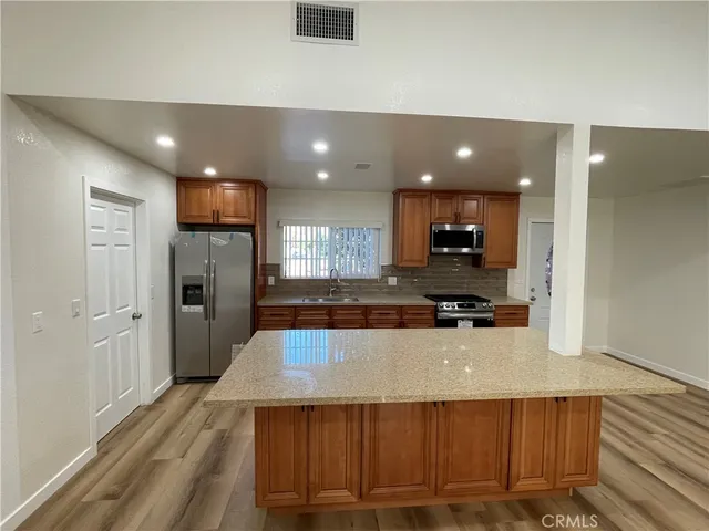 a large kitchen with stainless steel appliances a large counter top a stove and a refrigerator