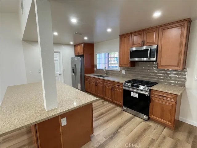 a kitchen with stainless steel appliances granite countertop a sink a stove and a refrigerator