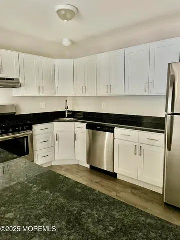 a kitchen with granite countertop white cabinets and stainless steel appliances