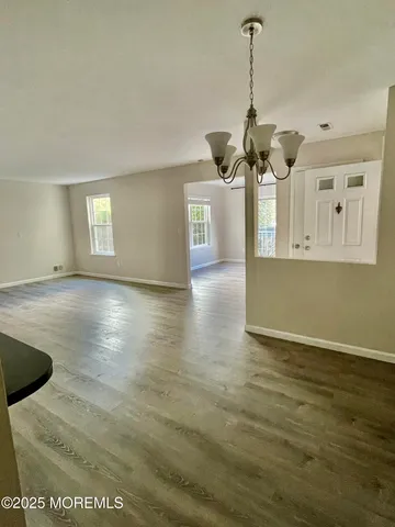 a view of a room with wooden floor ceiling fan and window