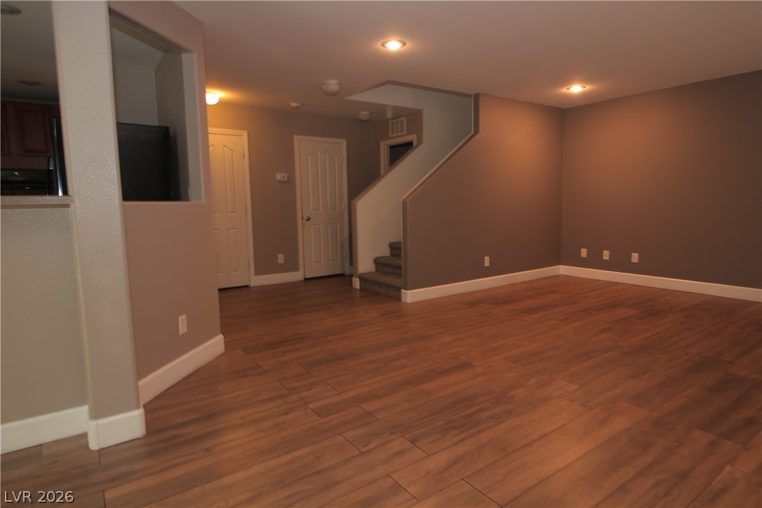 9289 Valley Ranch Avenue Las Vegas, NV 89178 - Photo 6 of 29 A spacious common area boasts wood-look tile flooring and recessed lighting, leading to a staircase and adjacent kitchen.