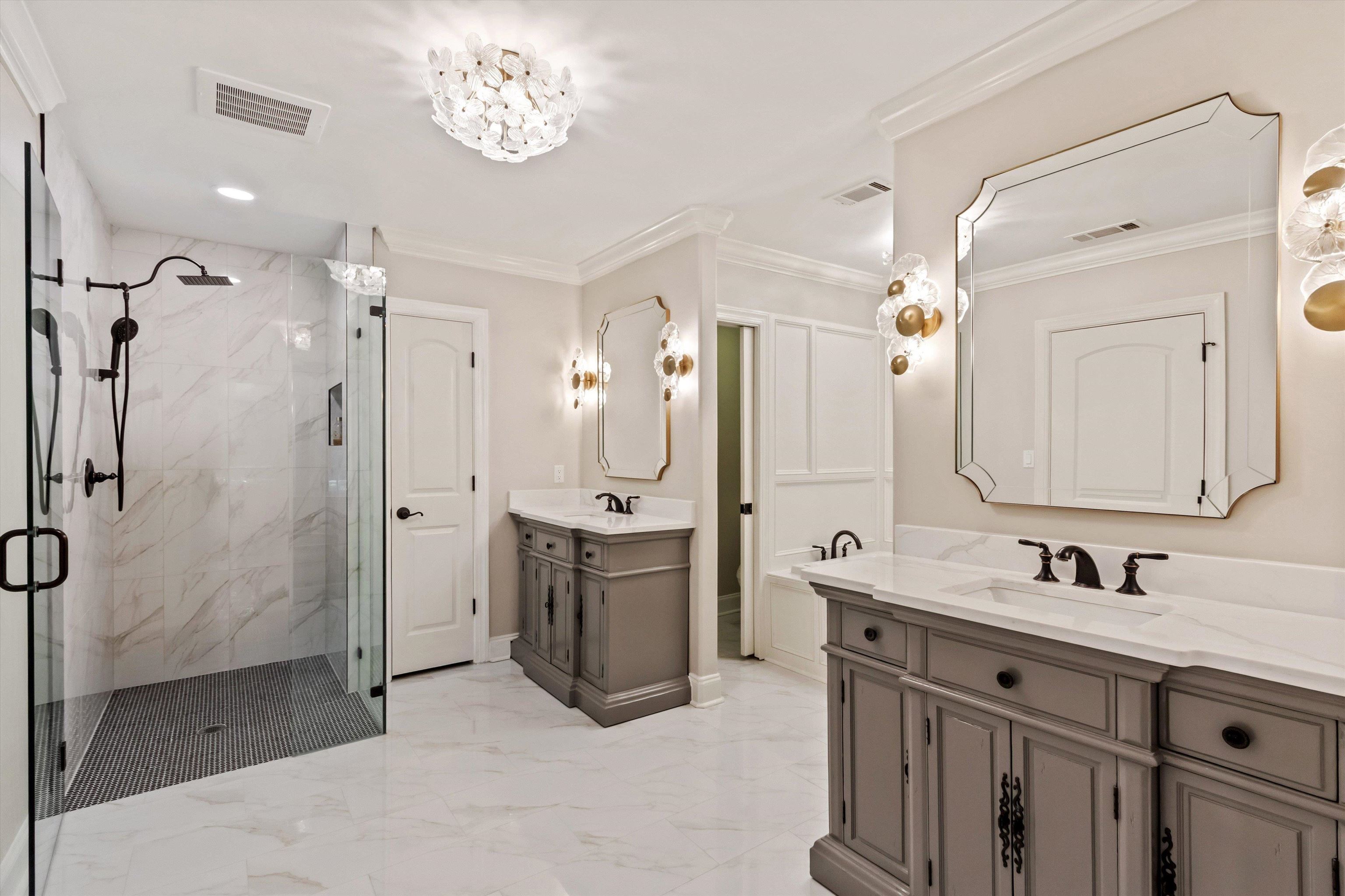 5302 South Angela Road Memphis, TN 38120 - Photo 22 of 40 Spacious bathroom featuring a frameless glass shower enclosure, dual vanity sinks, white stone countertops, and ornate wall sconces