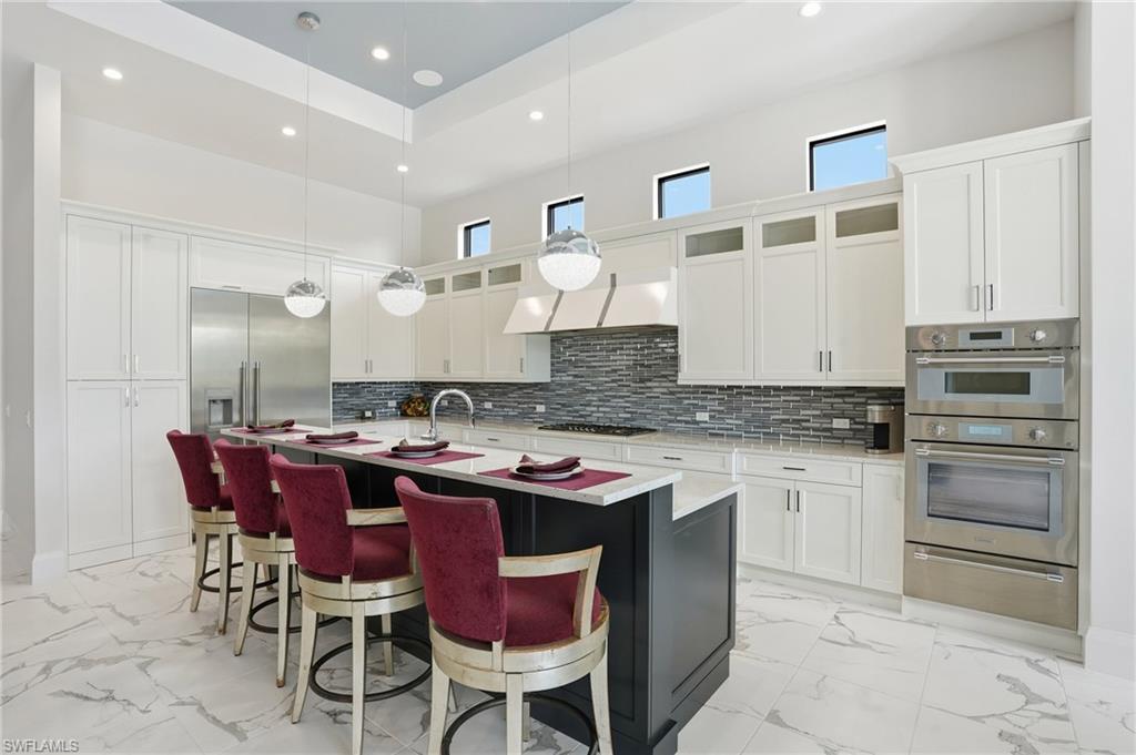 19086 Via Messina Way Miromar Lakes, FL 33913 - Photo 13 of 50 a kitchen with a stove a sink a dining table and chairs