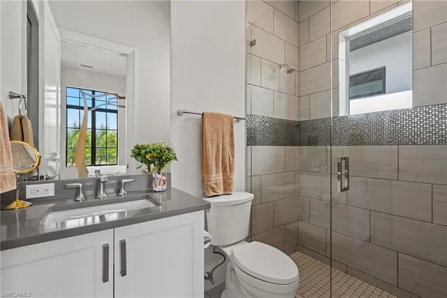 a bathroom with a granite countertop sink a toilet a mirror and shower