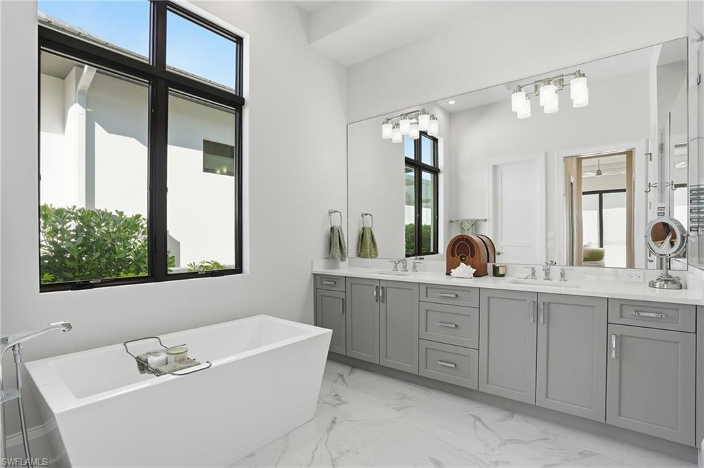 19086 Via Messina Way Miromar Lakes, FL 33913 - Photo 18 of 50 a bathroom with a tub a sink a window and mirror