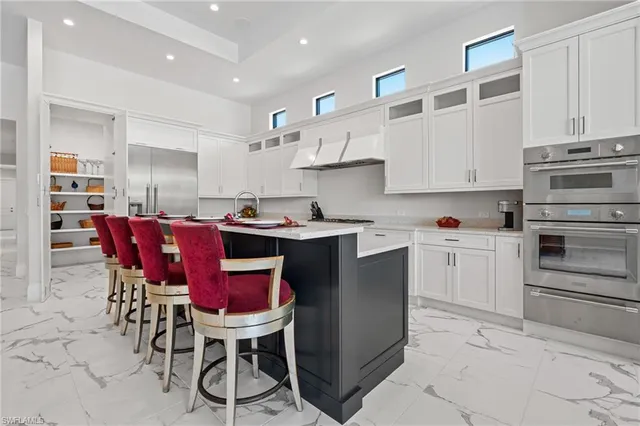 a kitchen with stainless steel appliances kitchen island granite countertop a table chairs and a refrigerator