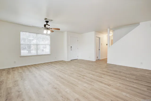 a view of empty room with wooden floor and fan