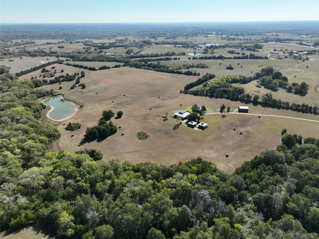 an aerial view of a house with a yard and lake view in back