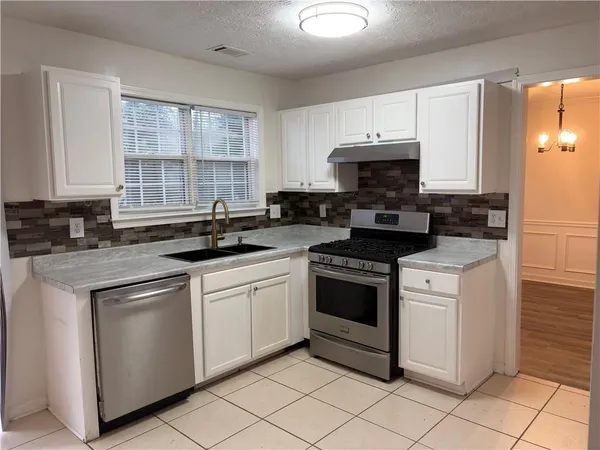 a kitchen with stainless steel appliances granite countertop a stove a sink and a microwave