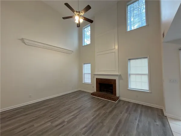 an empty room with wooden floor fireplace and ceiling fan