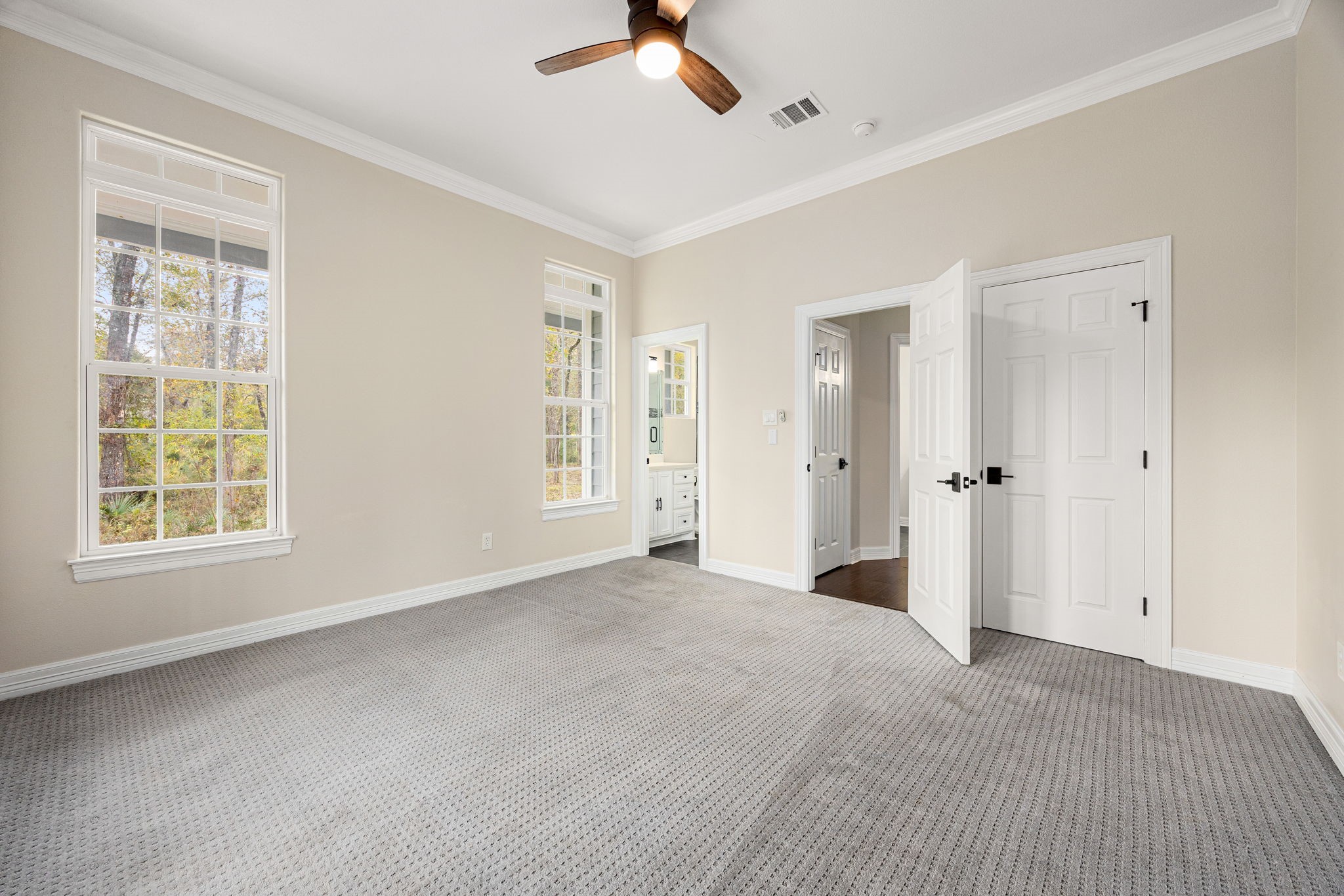 14882 Gingham Road Montgomery, TX 77356 - Photo 22 of 41 This spacious bedroom features large windows for ample natural light, neutral walls, and carpeted flooring. It includes a ceiling fan, an ensuite bathroom, and a walk-in closet, offering comfort and convenience.