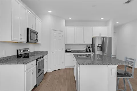 a kitchen with stainless steel appliances granite countertop a sink stove microwave and refrigerator