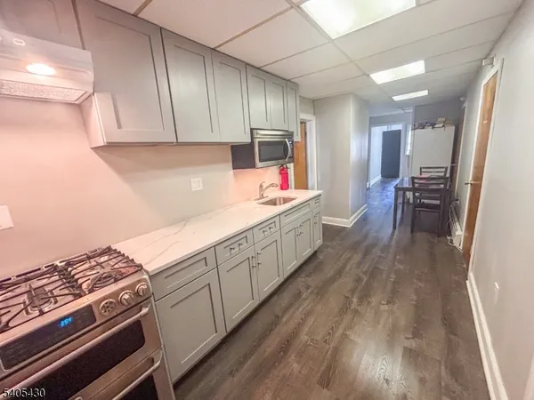 a kitchen with stainless steel appliances hardwood floor sink stove and wooden cabinets