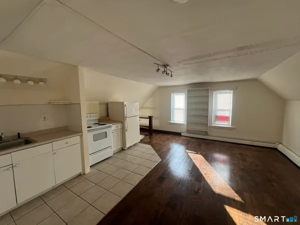 a kitchen with granite countertop a stove a sink and white cabinets with wooden floor
