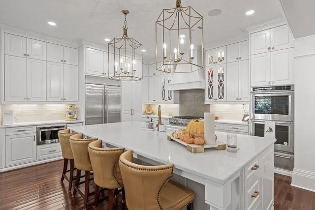 a kitchen with stainless steel appliances granite countertop a sink dishwasher and white cabinets with wooden floor