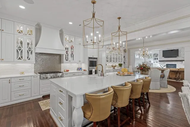 a kitchen with stainless steel appliances a sink dishwasher a refrigerator a stove and white cabinets with wooden floor