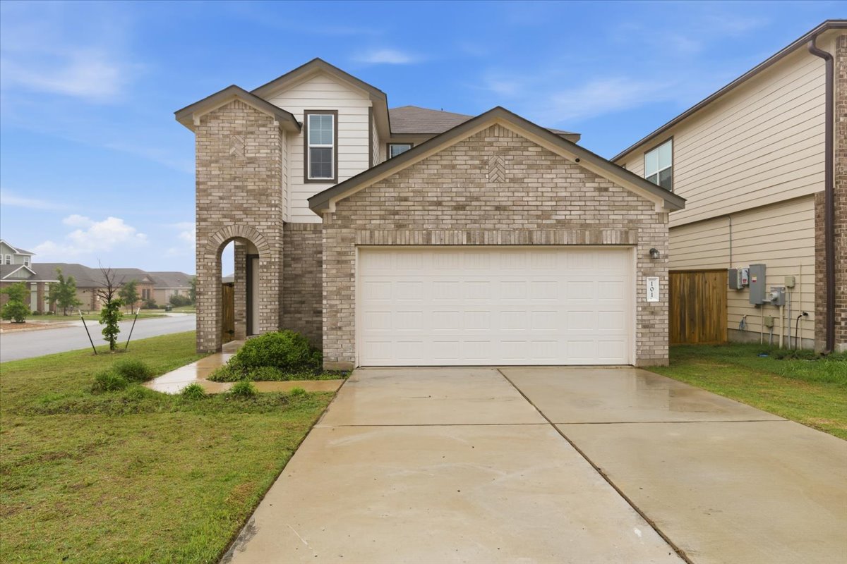 101 Rowdy Yates Way Jarrell, TX 76537 - Photo 1 of 32 Brick and siding exterior featuring an attached garage and arched entryway