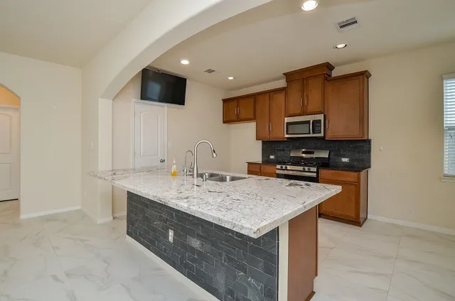 a kitchen with stainless steel appliances granite countertop a sink stove and microwave