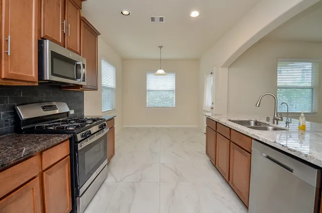 a kitchen with stainless steel appliances granite countertop a sink stove and microwave
