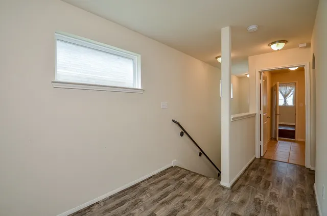 a view of a hallway with wooden floor and a bathroom